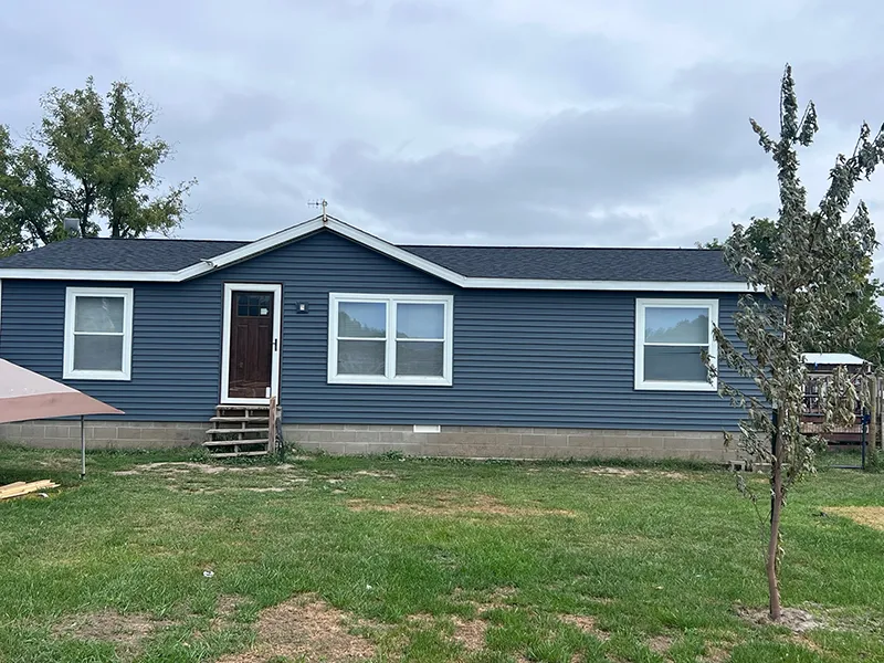 Single-story house with dark blue siding, white trim, and a small front porch.
