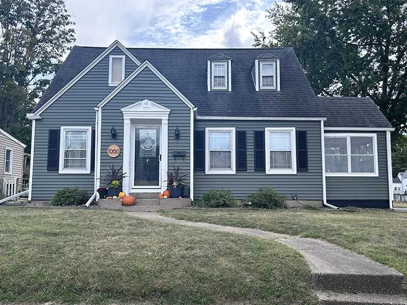 Charming gray house with black shutters, a curved pathway, and autumn decorations, Morton, IL Best Construction.