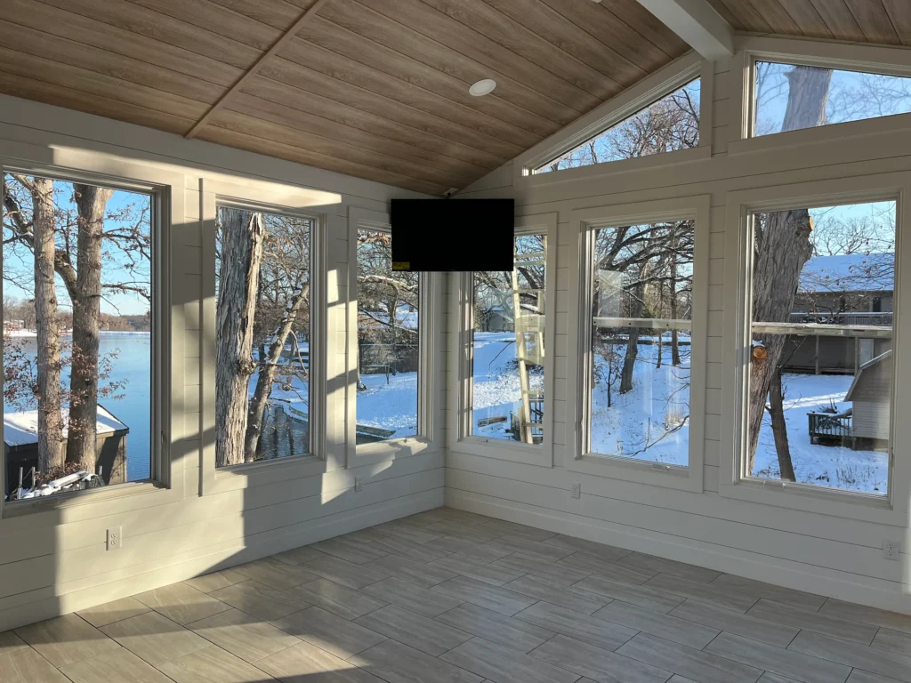 Bright sunroom addition with vaulted ceiling and panoramic windows, showcasing a home remodeling project by KB Builders
