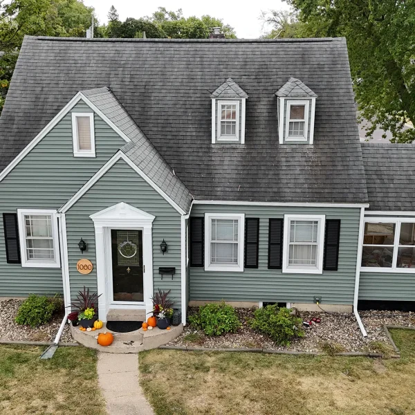 A house with light green siding and black shutters.